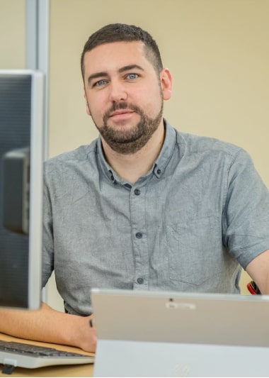 Philippe sitzt an einem Schreibtisch mit einem Laptop vor sich.