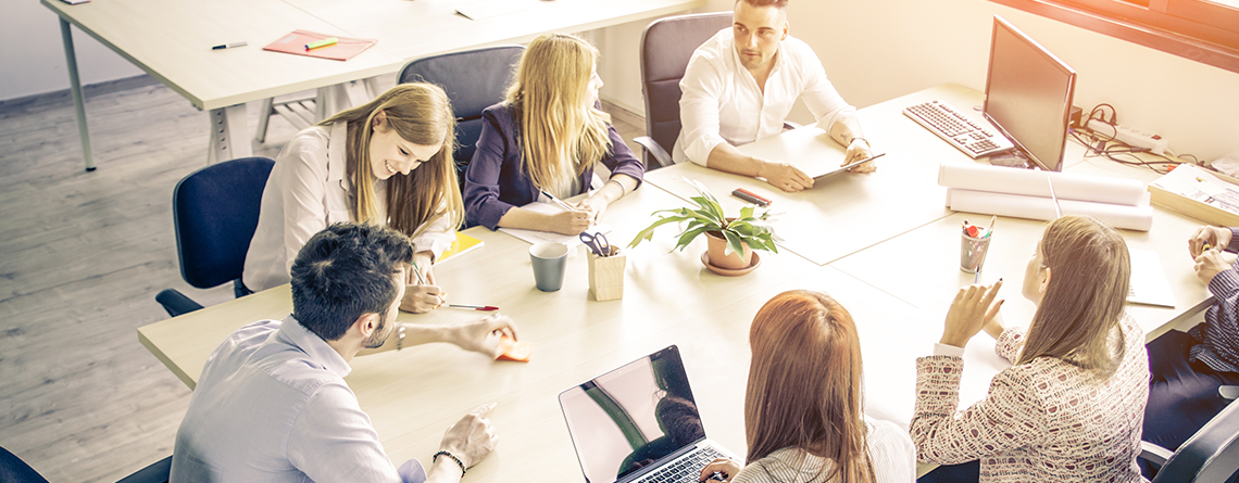 Eine Gruppe von Menschen sitzt an einem Konferenztisch und diskutiert die neuesten Trends in den Microsoft Cloud-Kommunikationskanälen.