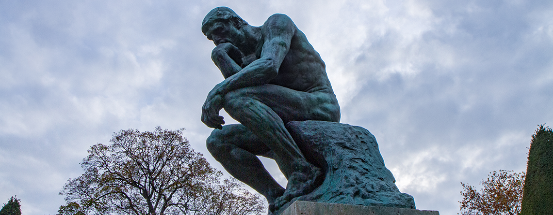 Eine Reihe-Statue des Denkers vor einem bewölkten Himmel, die tiefes Wissen und eine künstlerische ISO-Komposition demonstriert.